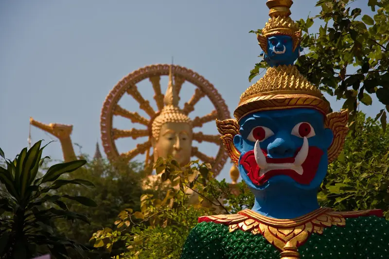 A painted temple guardian with the head of the Big Buddha and the Dharma wheel behind