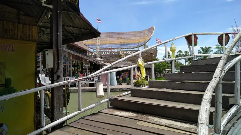 Entrance to Pattaya Floating Market: wooden walkway, bamboo railings and the Pattaya Floating Market sign above the canal