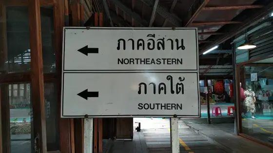 Thai and English direction sign in a covered gallery pointing to the Northeastern and Southern zones