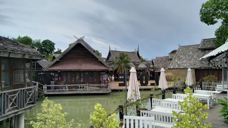 Thai-style houses over a canal and white tables by the water
