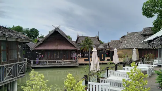 Thai-style houses over a canal and white tables by the water