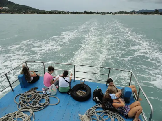 The stern of a ferry heading from Samui to Phangan, with the Samui shore on the horizon