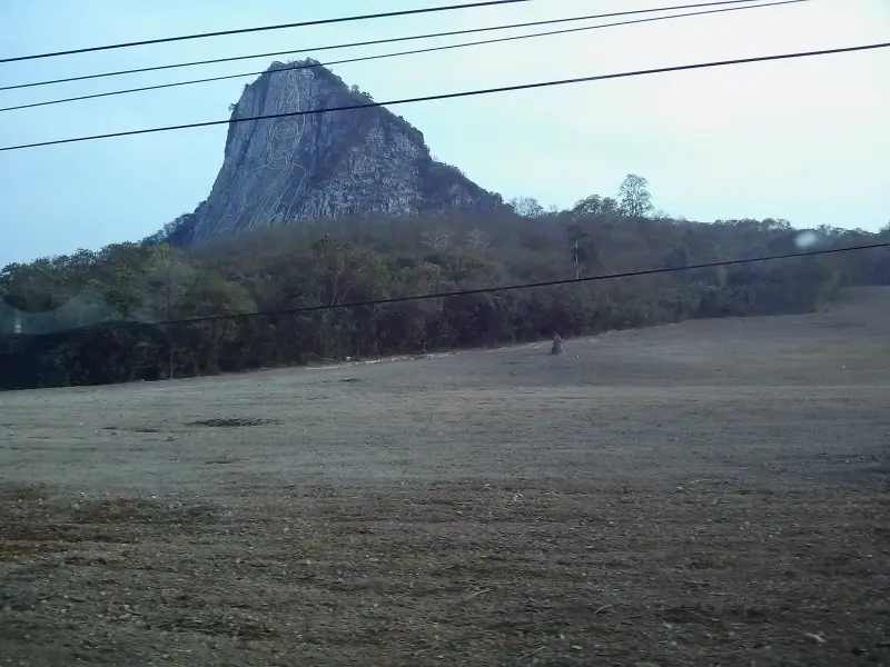 Khao Chi Chan seen from afar, the Buddha outline visible above the forest