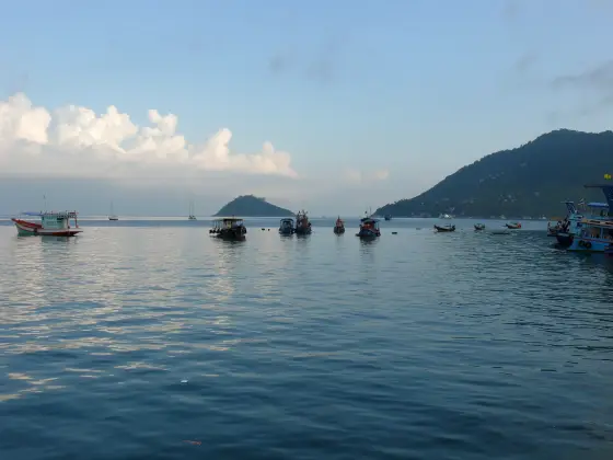 Boats on calm water off Koh Tao with a small island and the slope of Koh Tao beyond