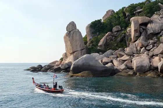 Granite rocks of Hin Tha Toh at the southern tip of Koh Tao and a longtail boat with tourists