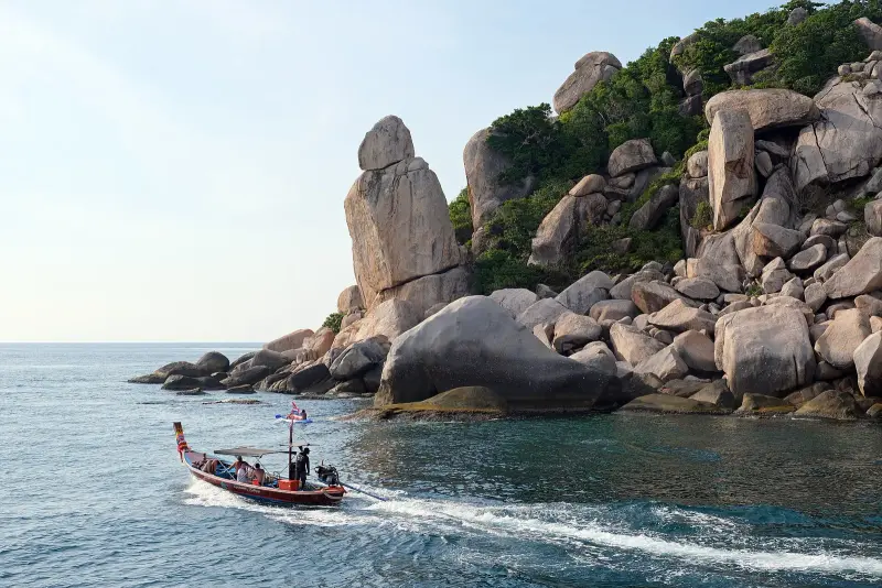 Granite rocks of Hin Tha Toh at the southern tip of Koh Tao and a longtail boat with tourists