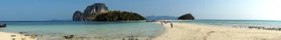 A sandbar at low tide between islands of the group, with people walking on it