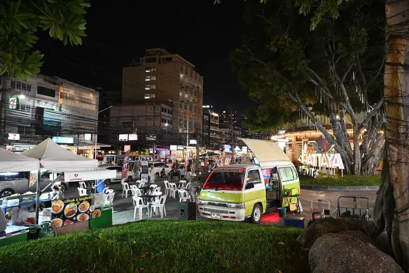 An evening square in Pattaya: a food tent, a food van and white plastic tables (the market is not named in the photo)