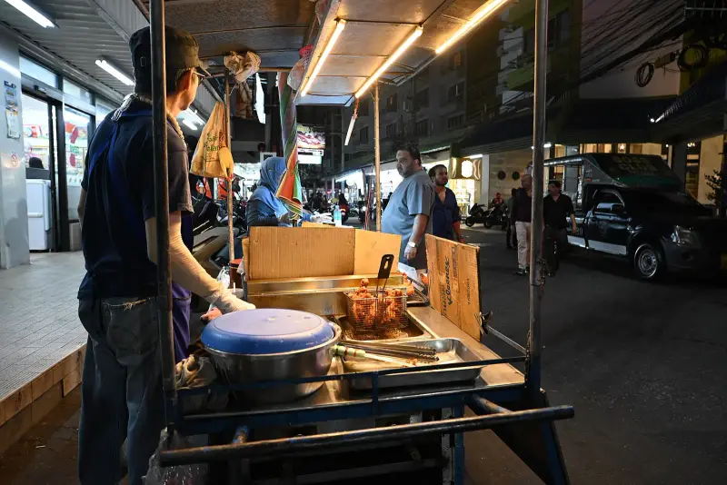 A street food cart on an evening street in Pattaya, a snack frying in a basket