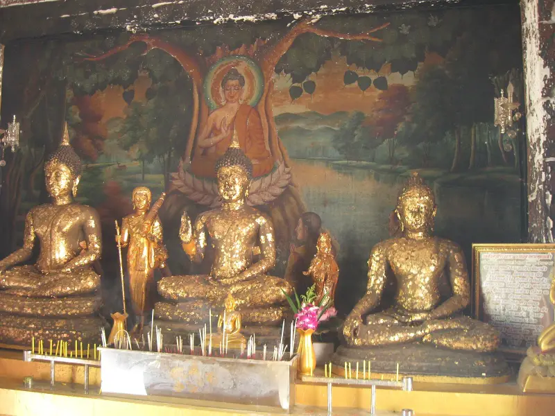 Gilded Buddha statues in front of a mural at Wat Khao Phra Bat on Pratumnak Hill