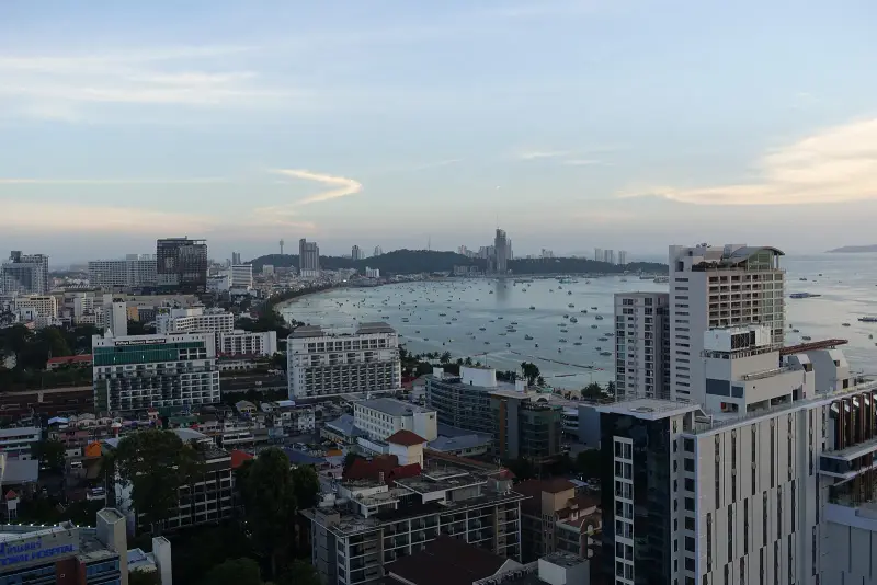 Evening view down on Pattaya Bay: the curve of the beach, boats on the water and hills on the far shore