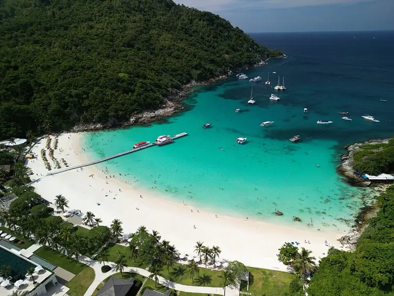 The west bay of Racha Yai with its pier, white beach and boats, seen from above